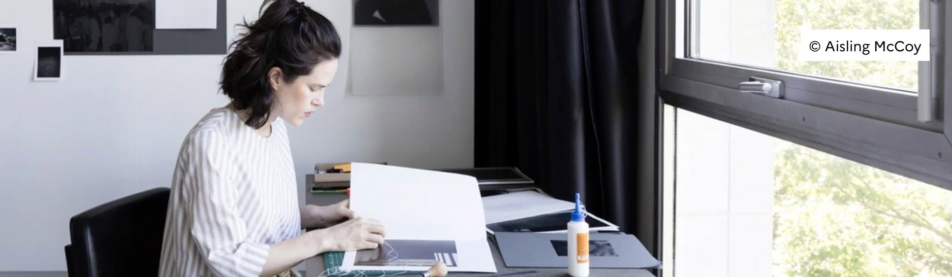 A person working at a table facing a window.